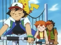 Ash, Misty y Brock montando en bici por el camino de bicis de Kanto.