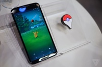 Foto de un smartphone con una versión beta de Pokémon GO y un Pokémon GO Plus.